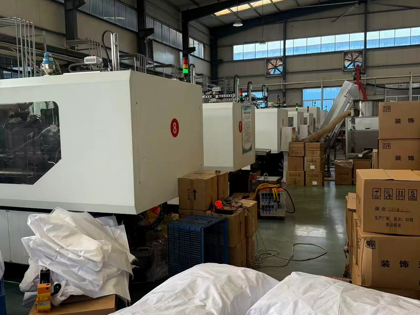 Injection moulding machine running on the factory floor with resin sacks alongside