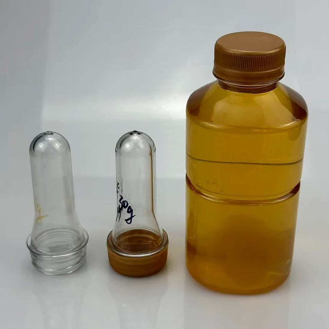 PET preform alongside the blown bottle and its closure